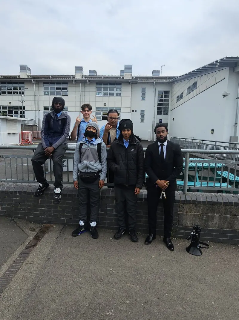 A mentoring group photographed together outside the school building.